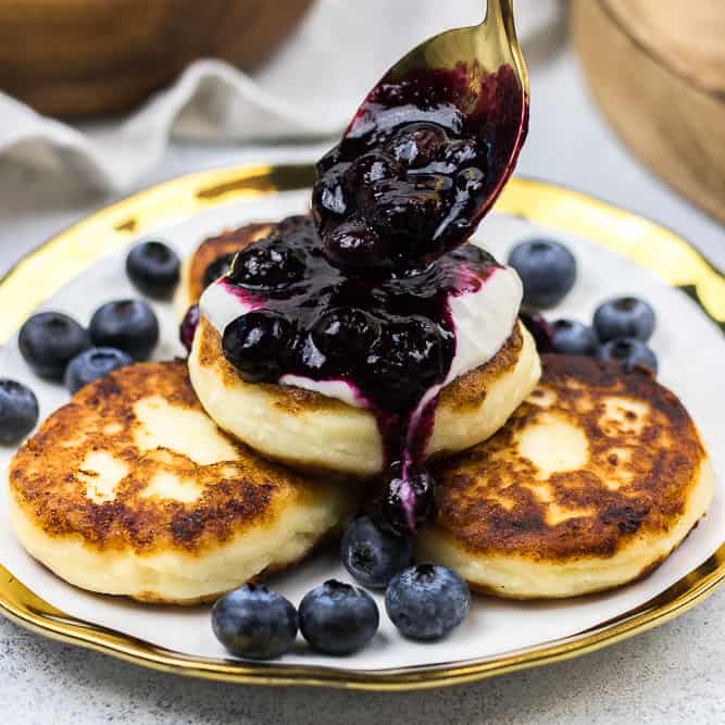 Golden syrniki cottage cheese pancakes with soured cream and berry compote