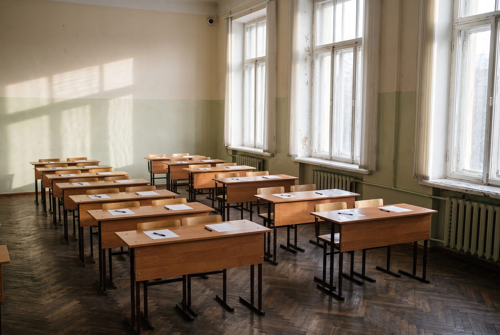 An empty Russian school hall laid out with individual desks for a state examination